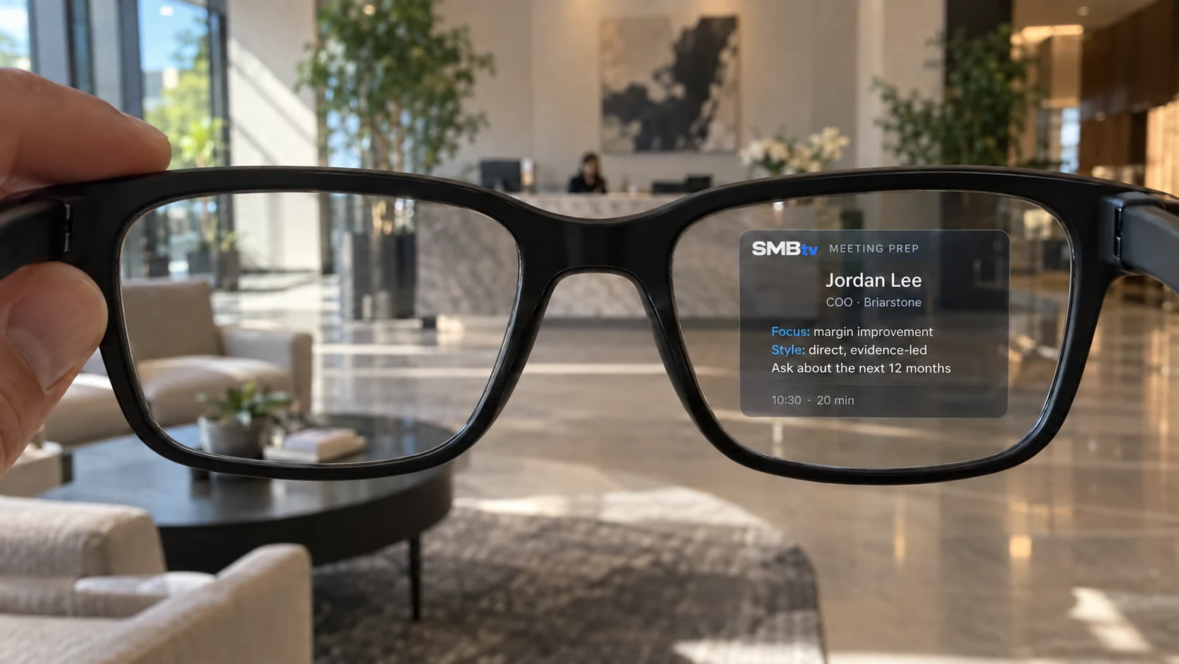 SMBtv meeting preparation for Jordan Lee projected entirely within the right lens of smart glasses in an office lobby
